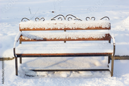 Wooden bench covered by sno...