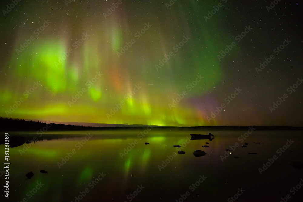 Colors of Light - Colorful northern lights bright up the starry night sky and a calm rocky lake.