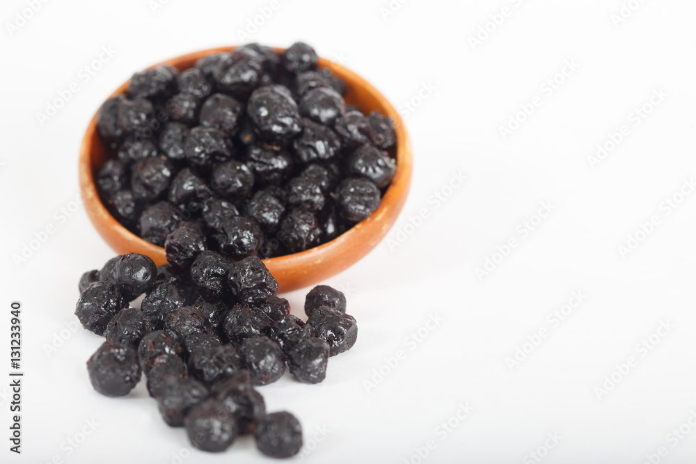 Dried blueberries fruit in wooden bowl on white background Dried blueberries fruit in wooden bowl on white background