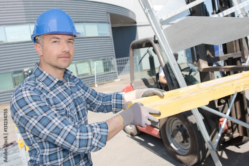 Worker loading wood on to forklift Worker loading wood on to forklift