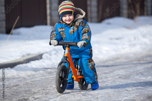 Child in ride balance bike (run bike) at winter