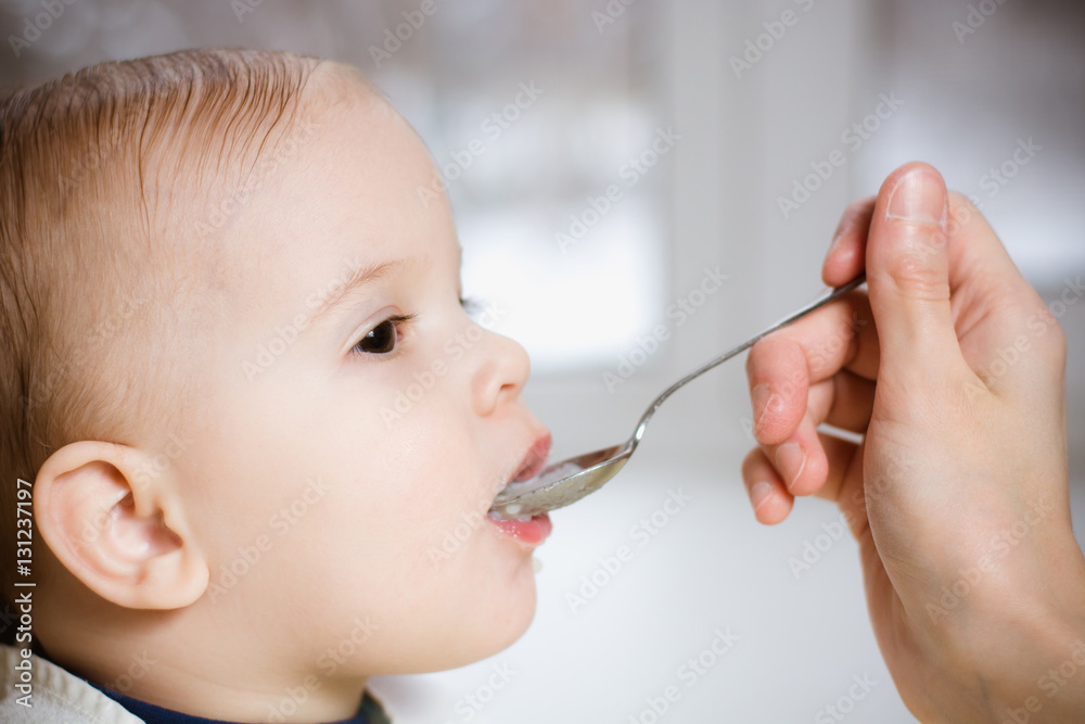 Mother gives baby food from a spoon Mother gives baby food from a spoon
