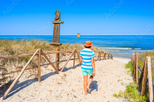 Young woman walking to sandy beach in Lubiatowo village, Baltic Sea, Poland photo