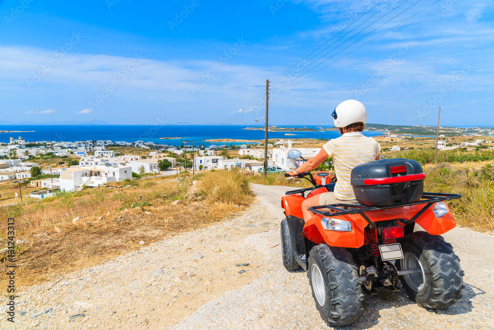 Obraz premium Young woman driving quad on gravel road on Paros island, Greece