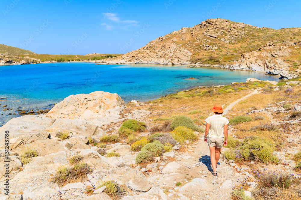 Young woman tourist walking along beautiful coast in Monastiri bay on Paros island, Greece