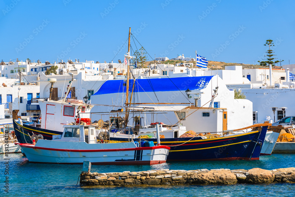 Fishing boats anchoring in front of a small church in Naoussa port, Paros island, Greece