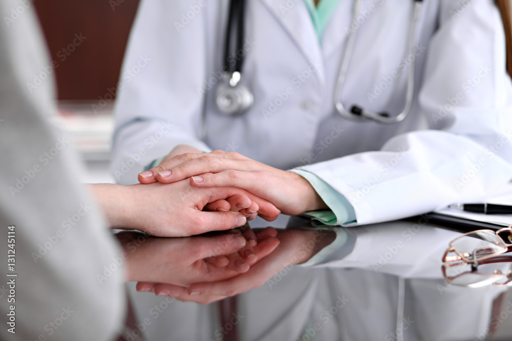 Obraz premium Friendly female doctor hands holding patient hand sitting at the desk for encouragement, empathy, cheering and support while medical examination. Bad news lessening, compassion, trust concept