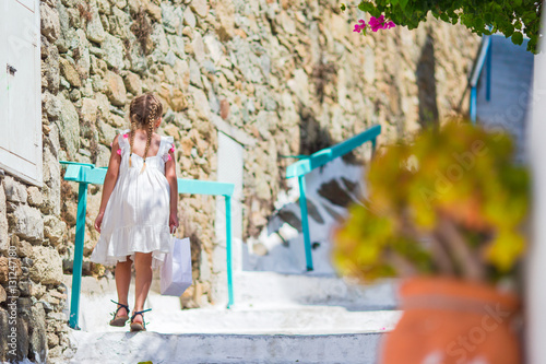 Adorable girl outdoors in greek village. Kid at street of typical greek traditional village with white stairs on greek island © travnikovstudio