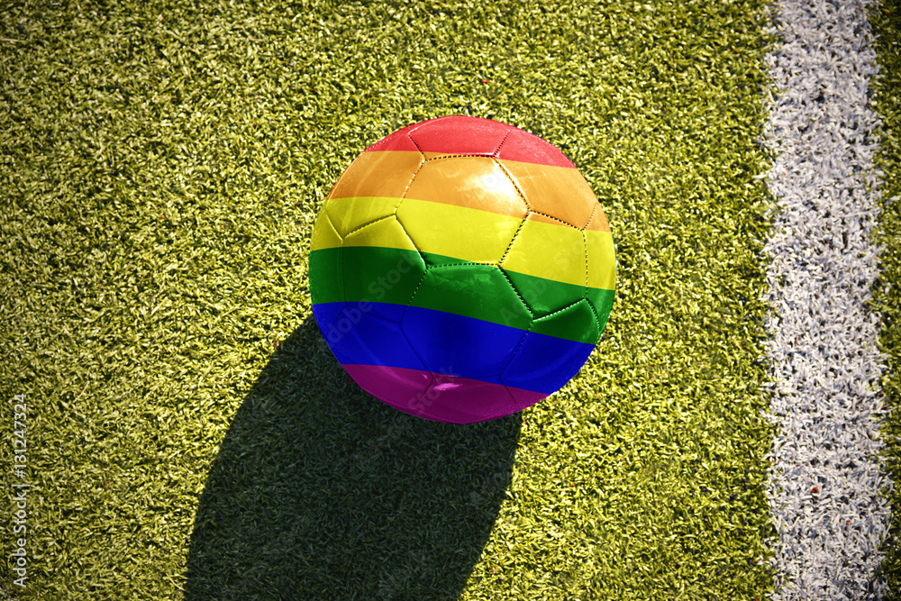 Naklejka premium football ball with the gay rainbow flag lies on the field