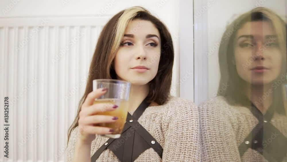 Pretty young brunette woman drinks from the glass by the window Pretty young brunette woman drinks from the glass by the window