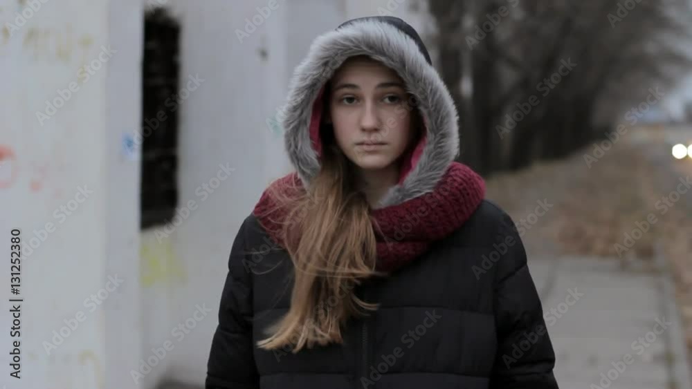 teen runaway: Sad lonely girl hood up standing near old road in cold dark weather, steadicam portrait shot teen runaway: Sad lonely girl hood up standing near old road in cold dark weather, steadicam portrait shot