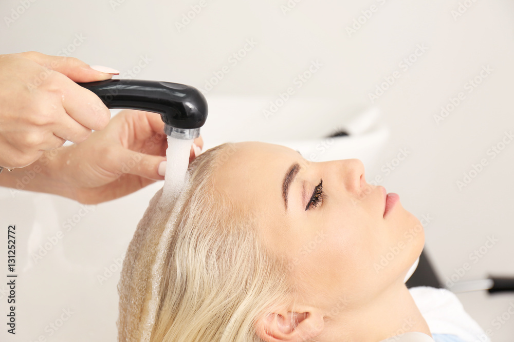 Fototapeta premium Hairdresser washing woman's hair in salon