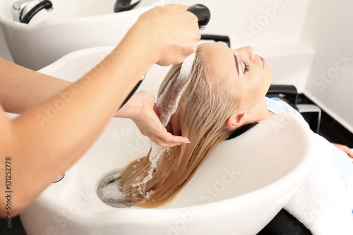 Hairdresser washing woman's hair in salon