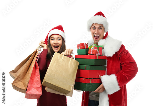 Young couple with Christmas purchases on white background