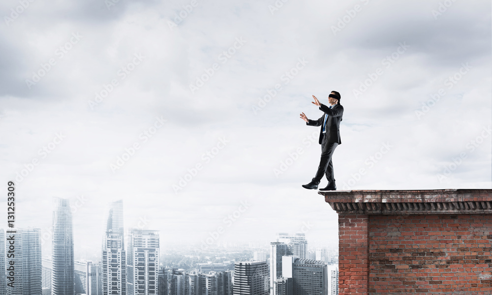 Danger and risk concept with businessman making step from edge Danger and risk concept with businessman making step from edge