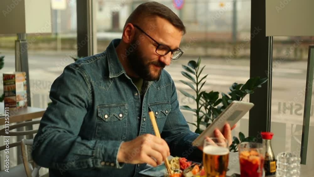Man reading something on tablet computer during meal in restaurant
Man reading something on tablet computer during meal in restaurant