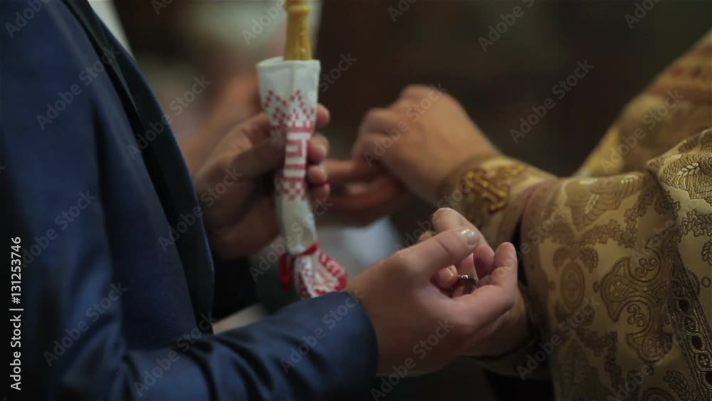 Orthodox priest performing rite of exchanging rings for marrying couple