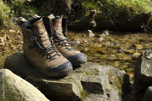 Old touristic shoes on a rock in a river
