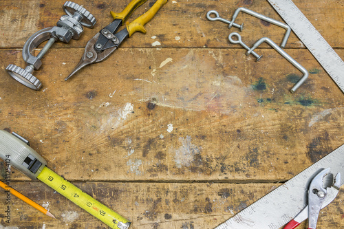 Tools along border of worn wooden workshop bench surface