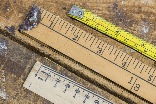Old yard stick, ruler and tape measure on scratched workshop tab