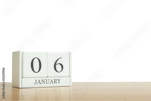 Closeup surface white wooden calendar with black 6 january word on blurred brown wood desk isolated on white background with copy space , selective focus at the calendar