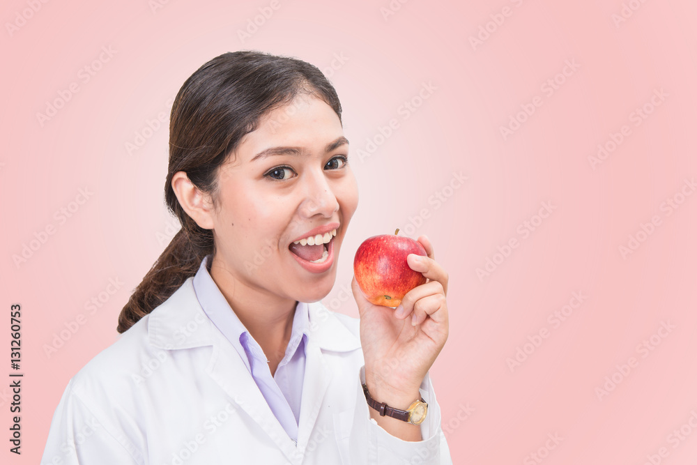 Young Asian female doctor eat apple isolated on pink background. Young Asian female doctor eat apple isolated on pink background.