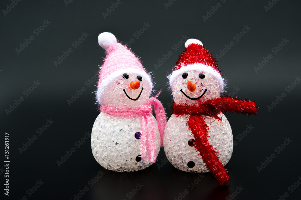two smiling toy christmas snowman on black background