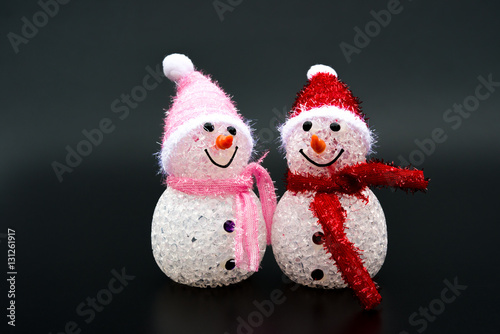 two smiling toy christmas snowman on black background