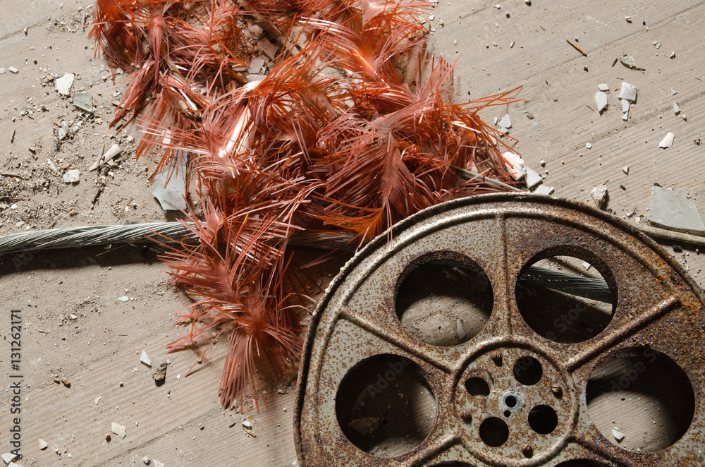 Naklejka premium An old metal rusty cinematography cinema film reel, that has been left in an abandoned cinema amongst concrete debris.