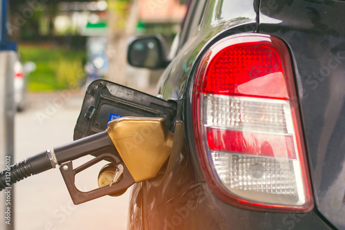 Fotografi Fuel nozzles adding gasoline fuel in car at a pump gas station
