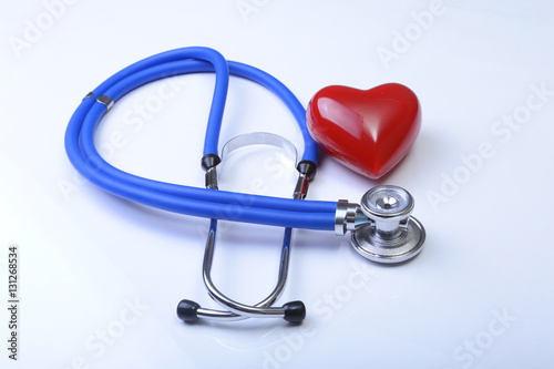 Cardiogram with stethoscope and red heart on table, closeup