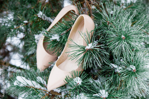 Pair of nude girl heels shoes on Christmas pine tree. Winter scene. Fashion ideas. Christmas background. 