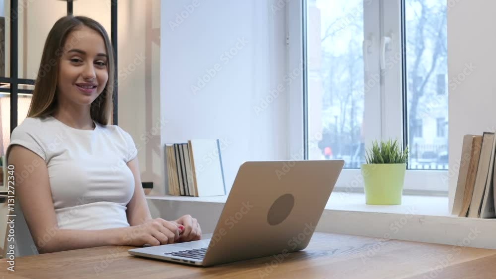 Young Girl Smiling Toward Camera while Working on Laptop Young Girl Smiling Toward Camera while Working on Laptop