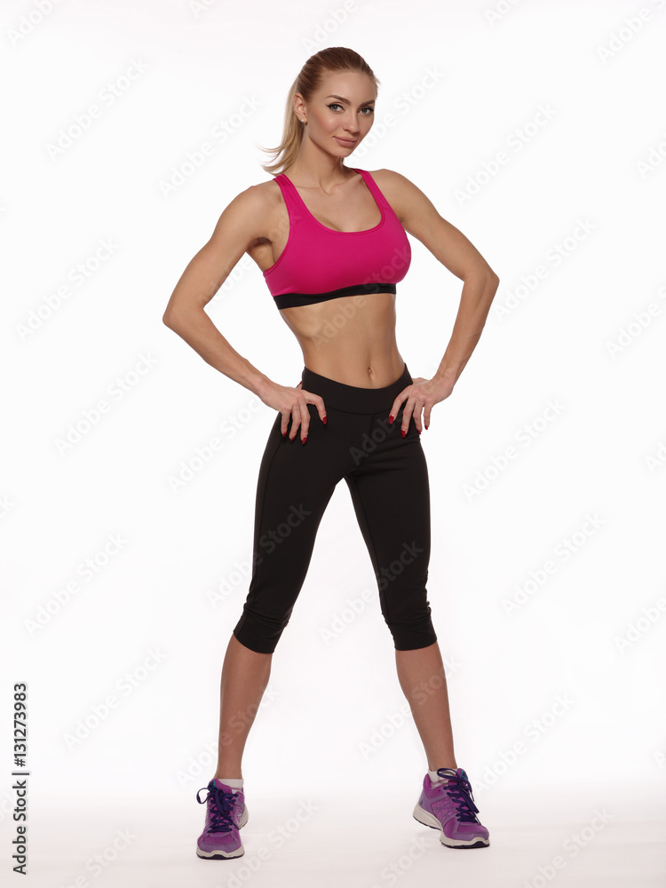 Beautiful athletic young woman with slim gorgeous body and collected hair wearing the sportswear is posing on the white isolated background, diet and fitness Beautiful athletic young woman with slim gorgeous body and collected hair wearing the sportswear is posing on the white isolated background, diet and fitness