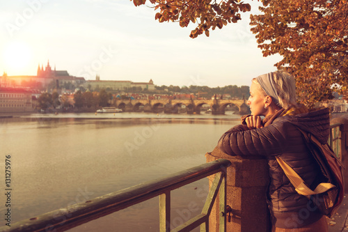 A young woman is looking at the sunset over a river Vltava in th