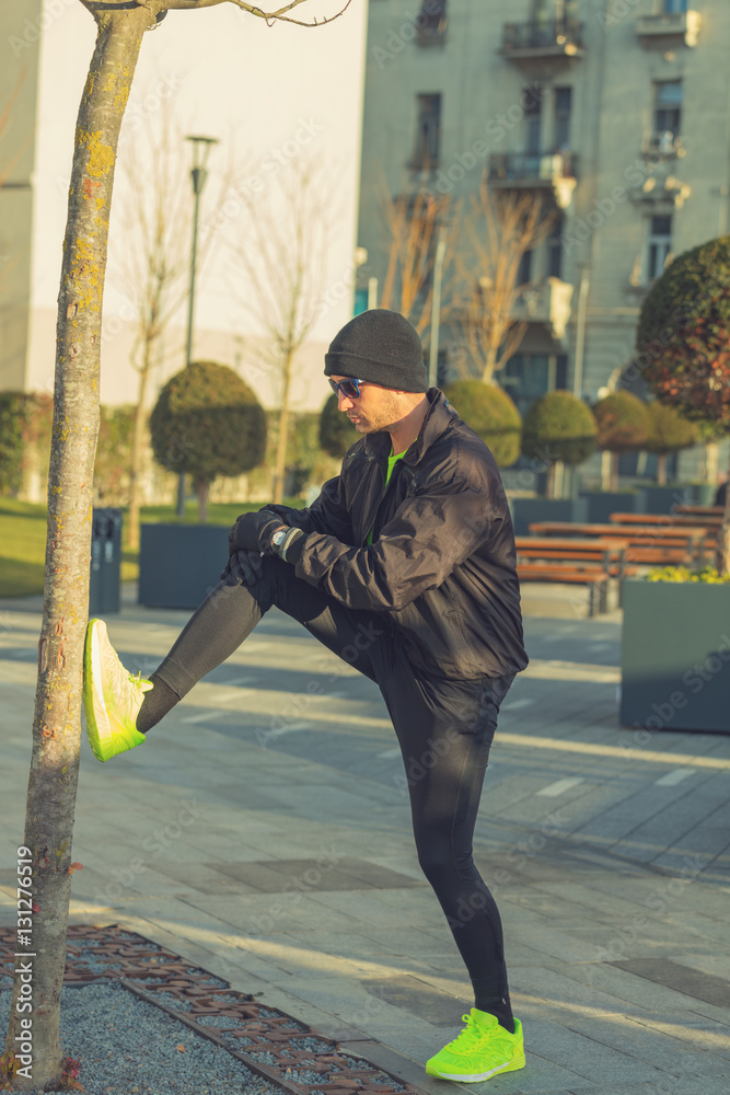 Urban jogger stretching in the park. Urban jogger stretching in the park.