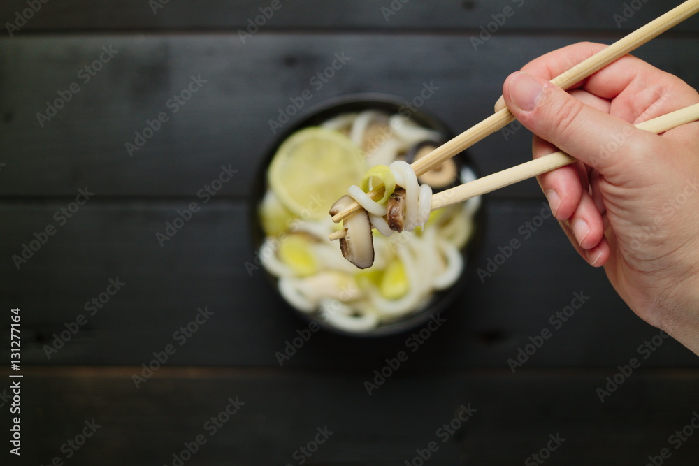 Eating japanese soup with udon noodles mushrooms leeks and lime Eating japanese soup with udon noodles mushrooms leeks and lime