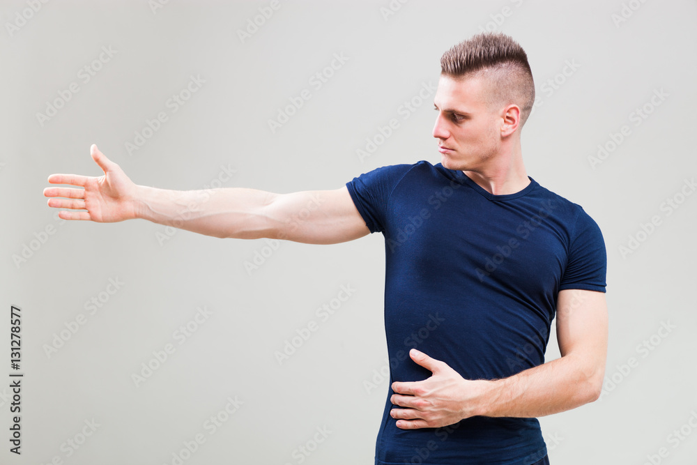 Studio shot image of young man who is stretching his body. 