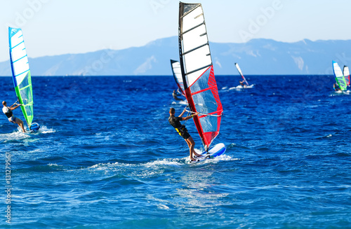 Side view of young windsurfer on background with other windsurfers