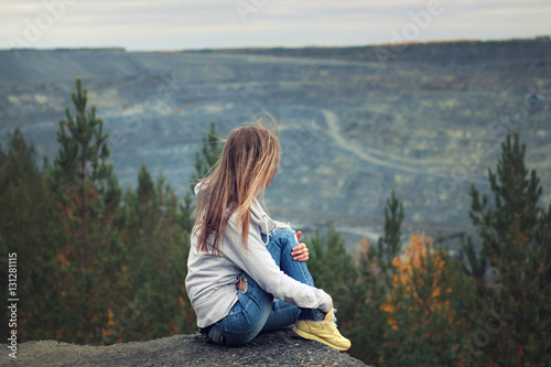Girl in torn jeans and a sweatshirt with a hood outdoors in autumn