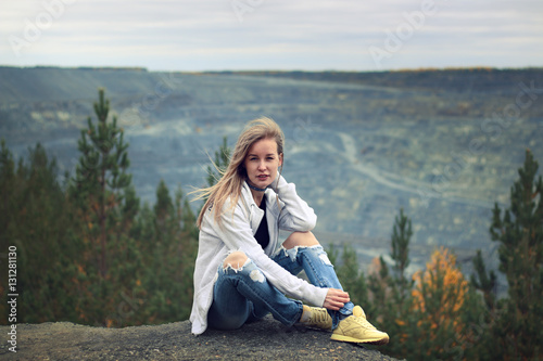 Girl in torn jeans and a sweatshirt with a hood outdoors in autumn