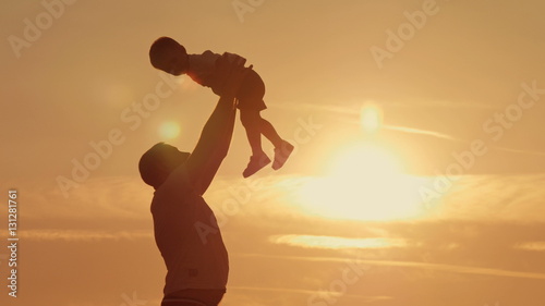 father and son silhouettes play at sunset beach. Happy family
