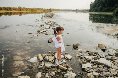a little girl standing on stones by the river