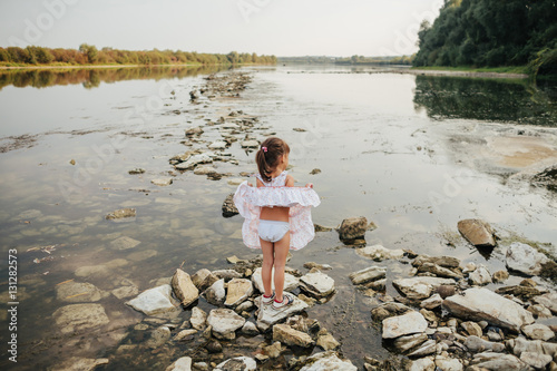 a little girl standing on stones by the river