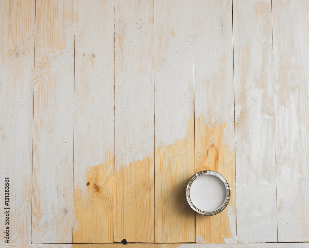 Open cans of paint on a wooden background. Partially painted with white Open cans of paint on a wooden background. Partially painted with white