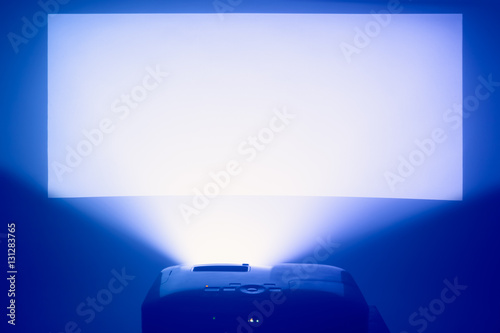 projector in action with illuminated warm blue screen background photo