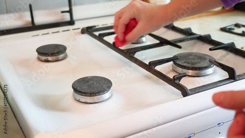 woman washes a gas stove in cleaning the kitchen