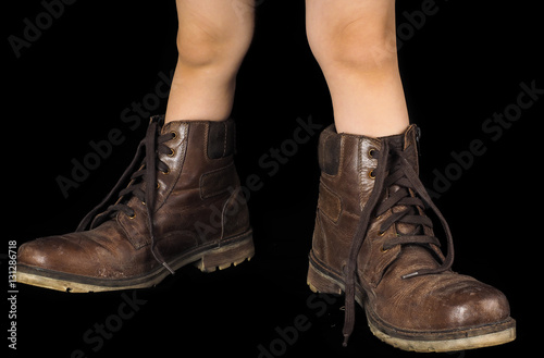Kid wearing a pair of too big untied and unpolished brown leathe