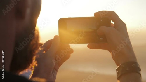 Young tourist man taking picture of sunset