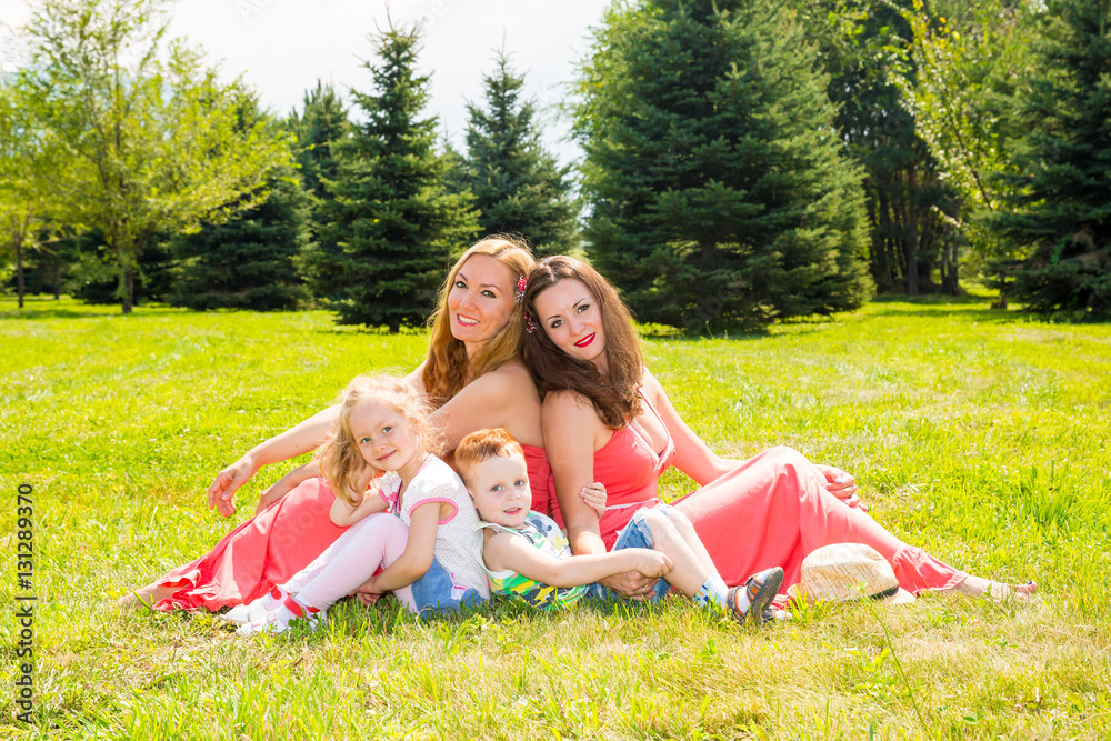 Fototapeta premium Happy family. Young mothers and kids boy and girl on sunny day. Portrait moms and children on nature. Positive human emotions, feelings, joy.